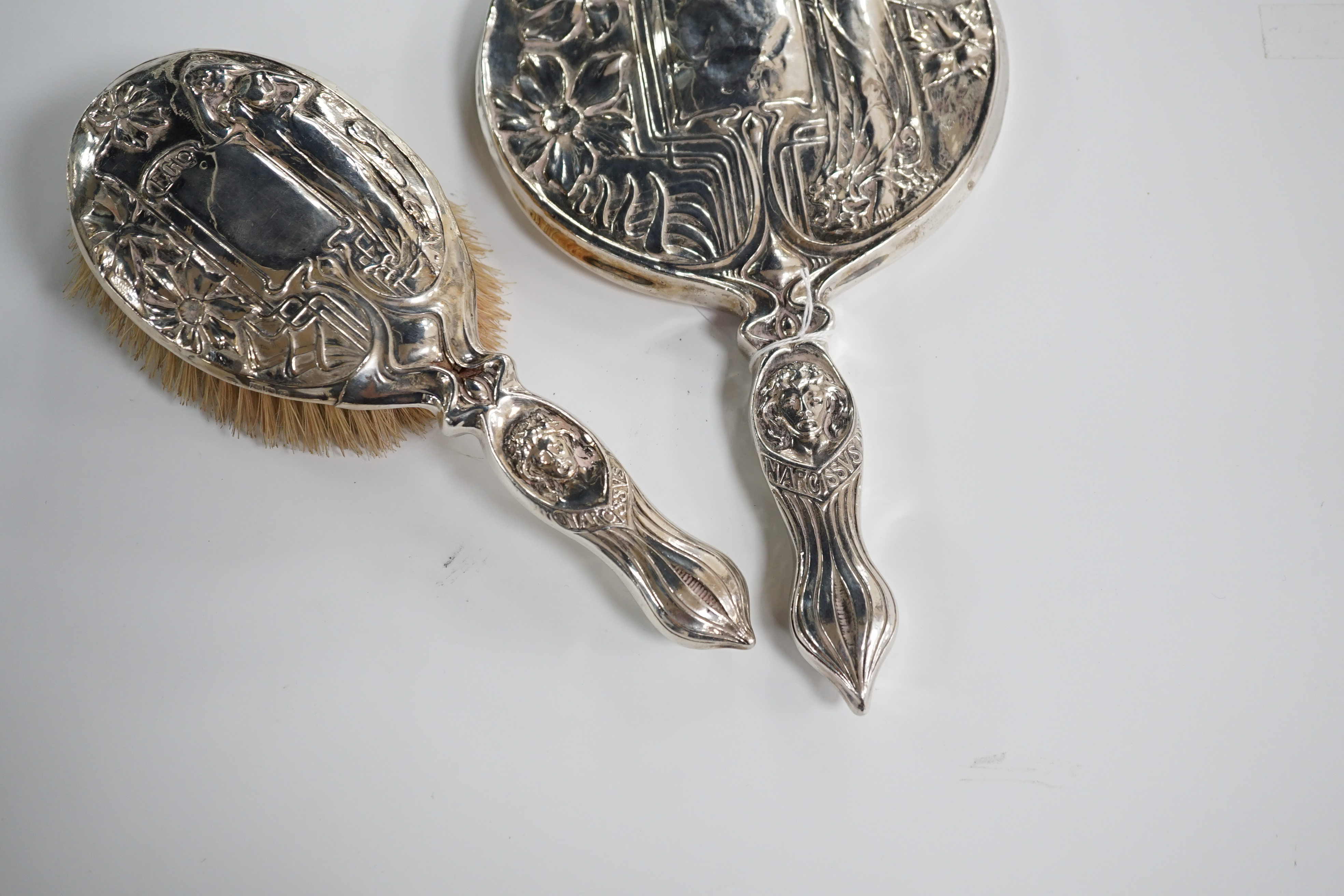A late Victorian Art Nouveau silver mounted hand mirror, marks rubbed, 27.8cm. and a later similar hair brush, London 1902. Condition - poor